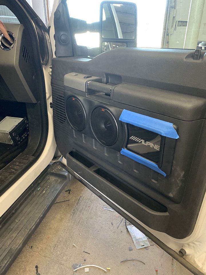 A person is working on a car door with speakers on it