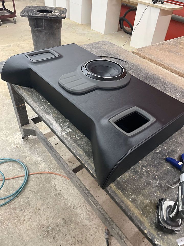 A black speaker box is sitting on top of a wooden table