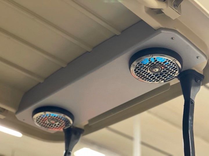 Two speakers are mounted to the ceiling of a golf cart