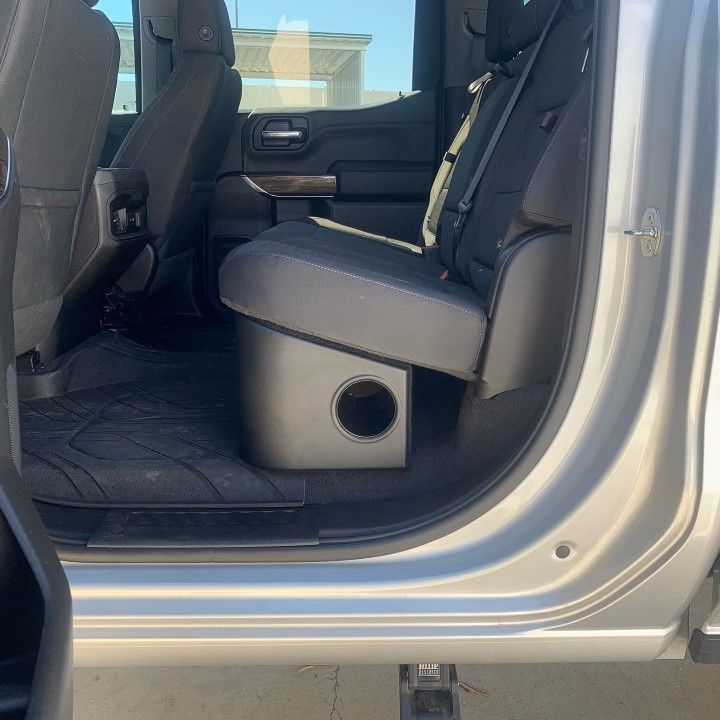 A silver truck with a subwoofer in the back seat