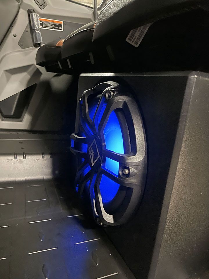 A subwoofer with a blue light on it is in the back of a vehicle