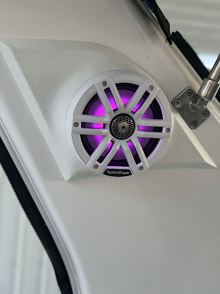 A white speaker with purple lights on a boat