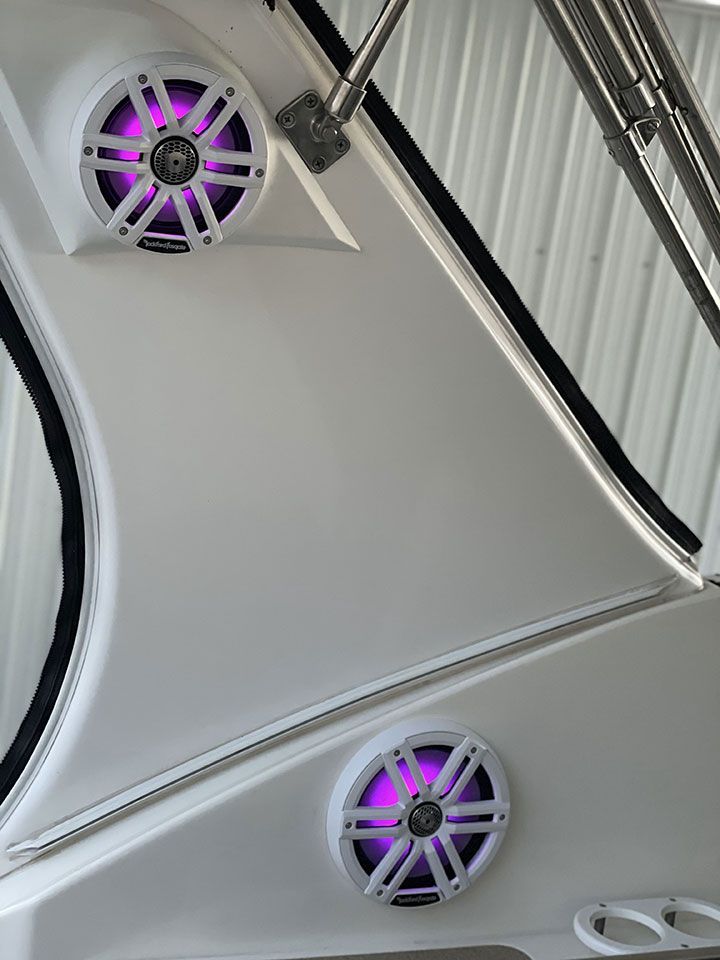 There are two speakers on the side of a boat with purple lights