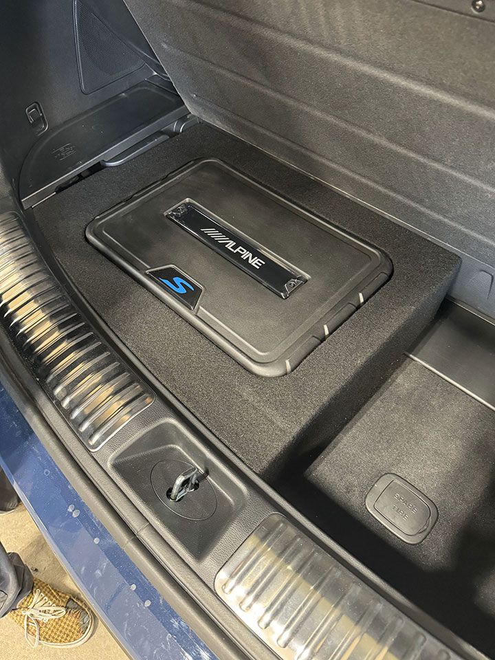 A subwoofer is sitting in the trunk of a car