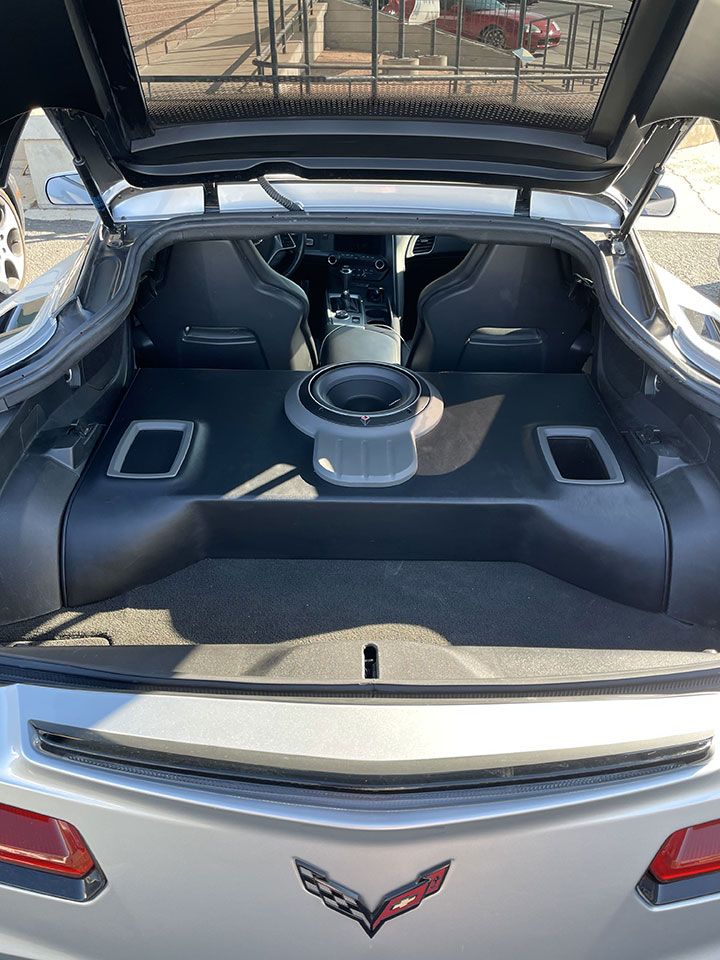 The back of a silver corvette with the trunk open