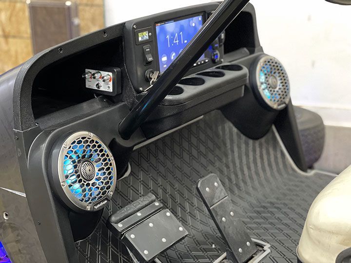 The dashboard of a golf cart with speakers and a radio