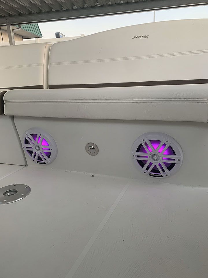 There are two speakers on the back of a boat with purple lights