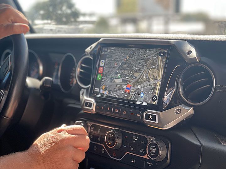 A person is driving a car with a navigation system on the dashboard