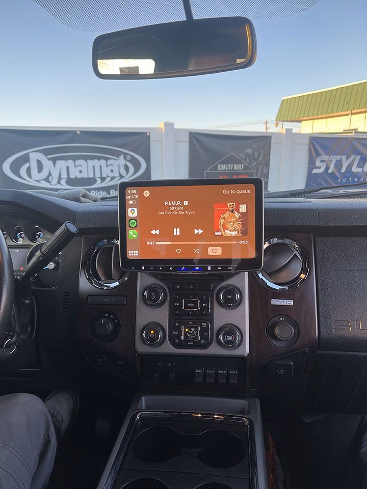A person is sitting in a car with a tablet on the dashboard