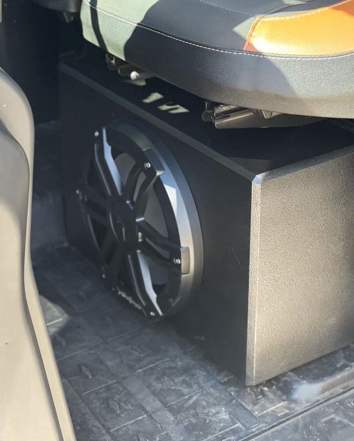 A subwoofer is sitting under a seat in a vehicle