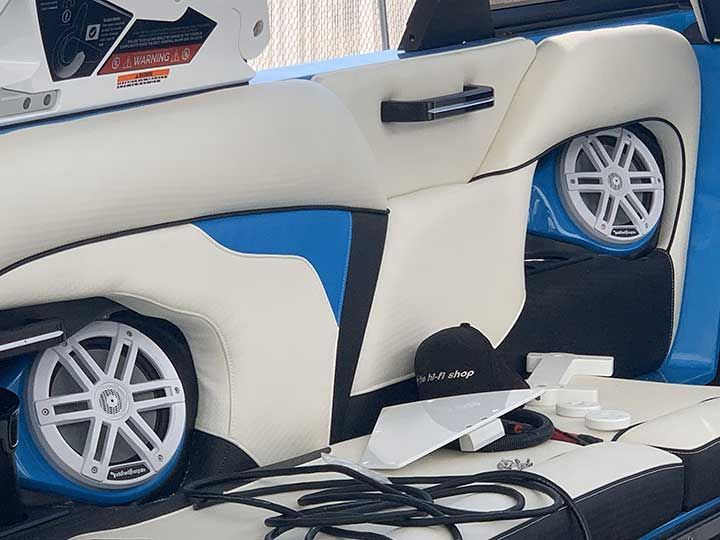 A blue and white boat with speakers in the back seat
