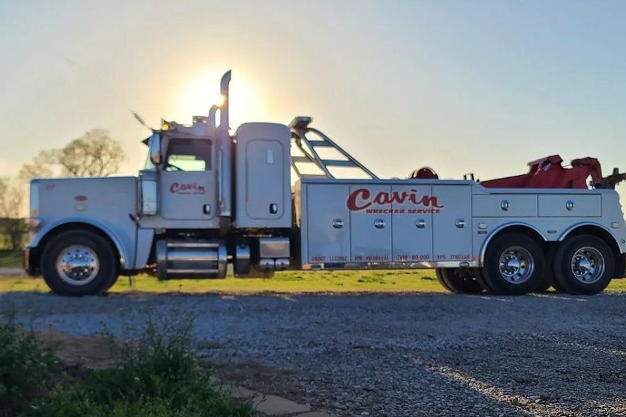 A white cavin tow truck is parked on the side of the road