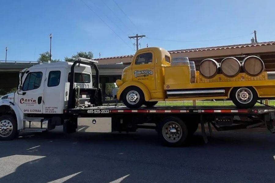 A yellow truck is sitting on top of a tow truck.
