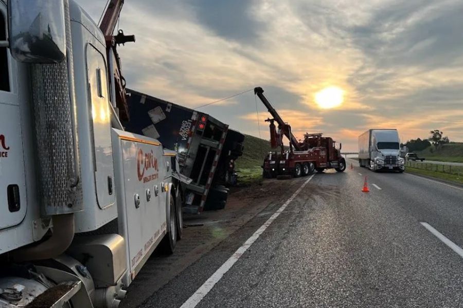 A tow truck is towing a truck that has fallen off the road.