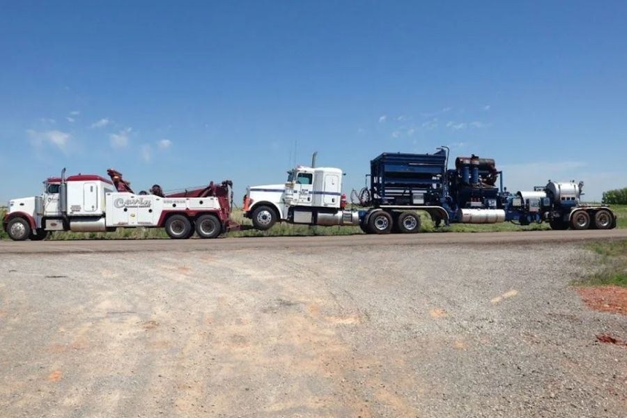 A row of tow trucks are parked on the side of the road.