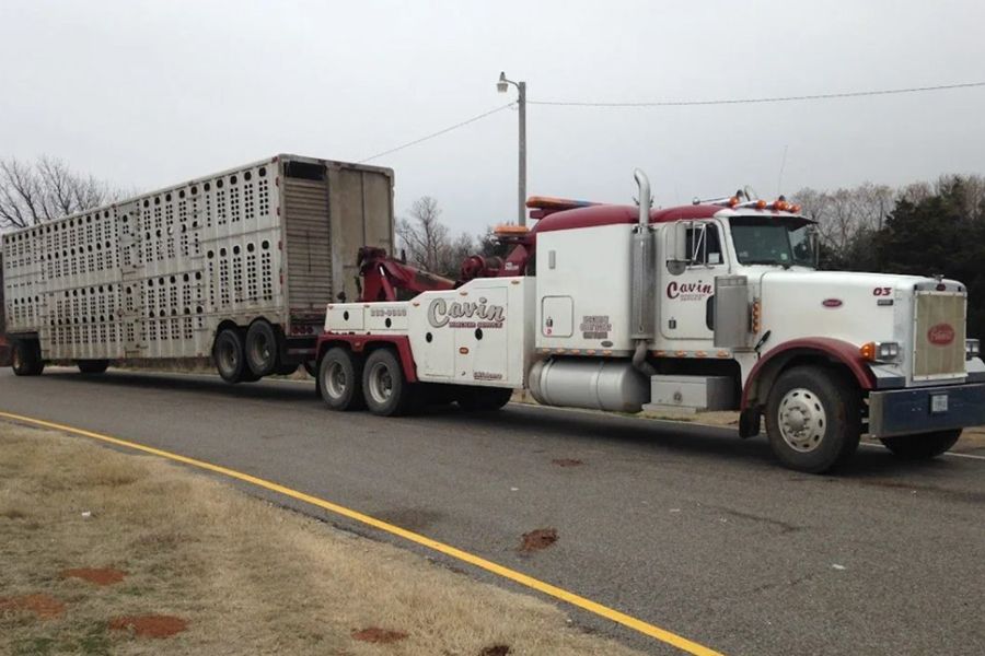 A tow truck with a trailer attached to it is driving down a road.