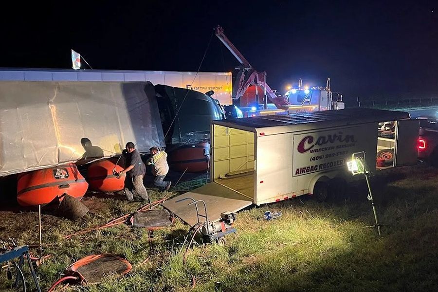 A group of people are working on a truck in a field at night.