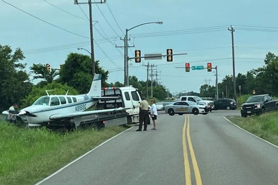 A small plane is sitting on the side of the road.