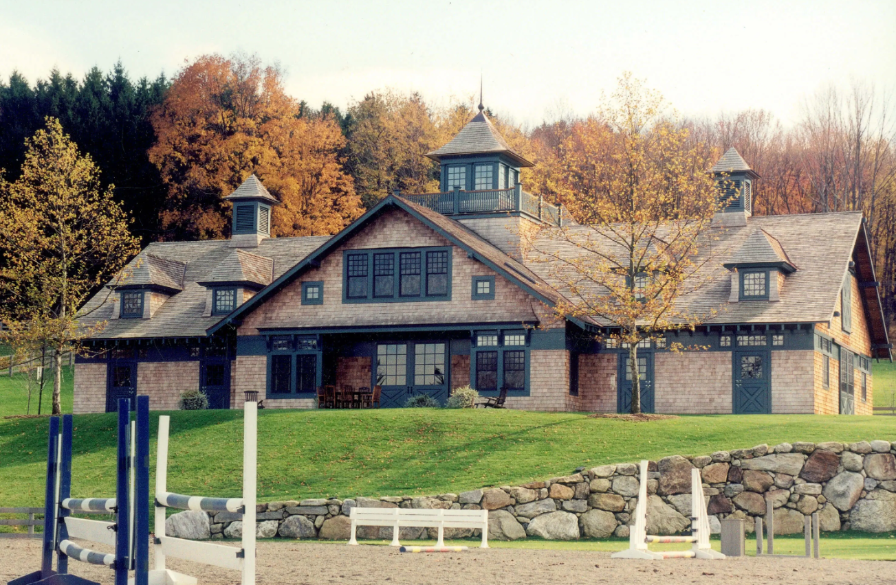 Stone house with blue-trimmed windows and autumn trees in front of a grassy yard