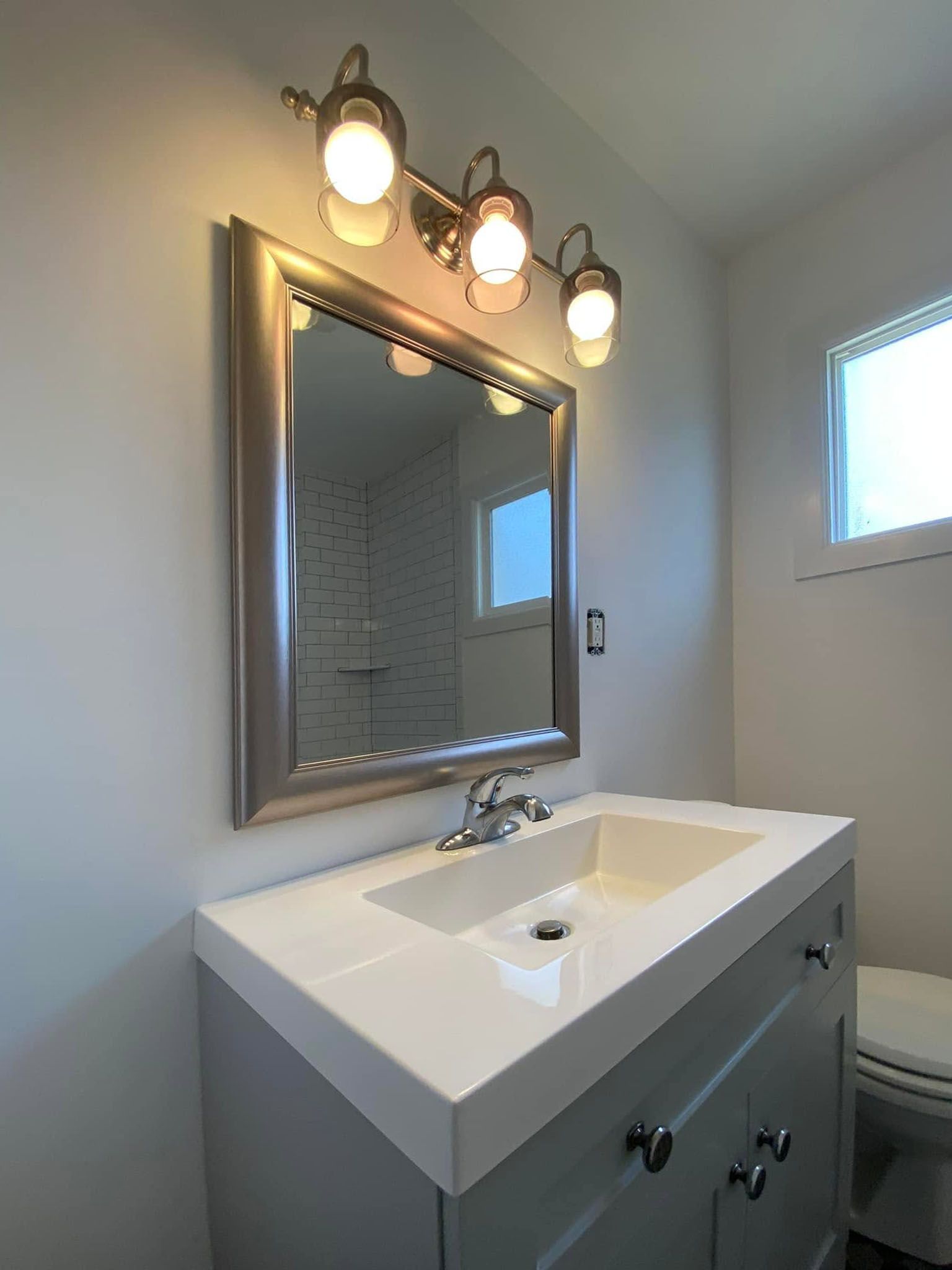 Bathroom vanity with lit mirror, white sink, and chrome faucet in a bright modern room.