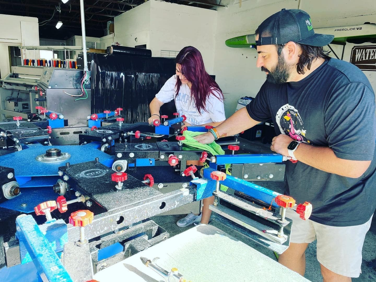 People playing foosball at an indoor arcade table, with colorful handles and coins visible.