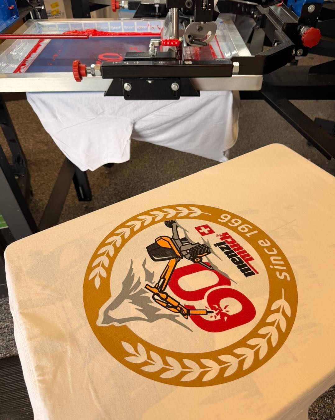 T-shirt on a heat press, with a gold and red leaping tiger-style graphic design.