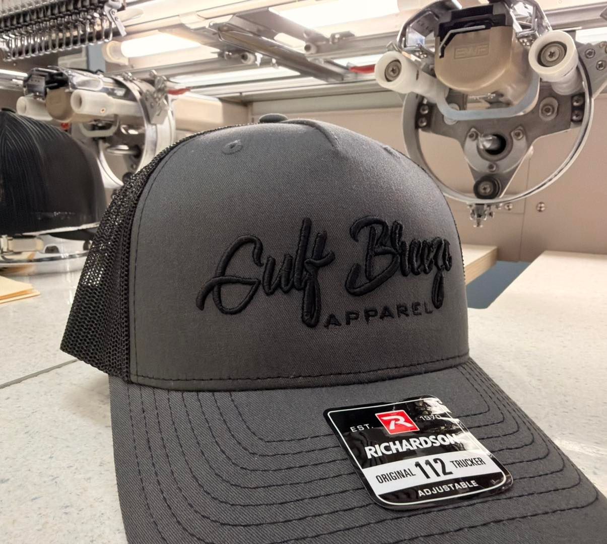 Gray mesh-and-black trucker hat with “Gulf Breeze Apparel” logo and a “Black Friday” sale tag.