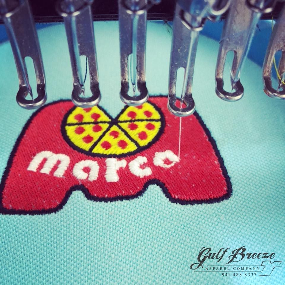 Close-up of a red Mars candy logo stitched on blue fabric, with a yellow heart-shaped center