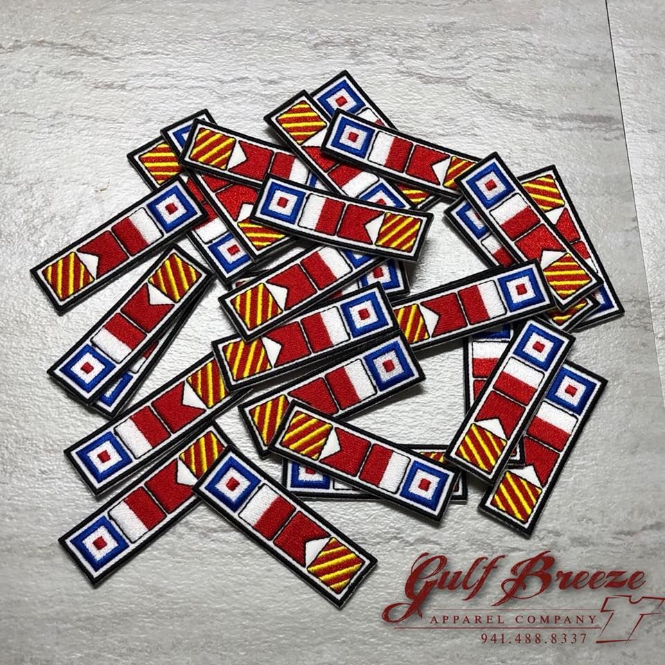 Scattered colorful dominoes on a light textured surface with a Gulf Breeze logo in the corner