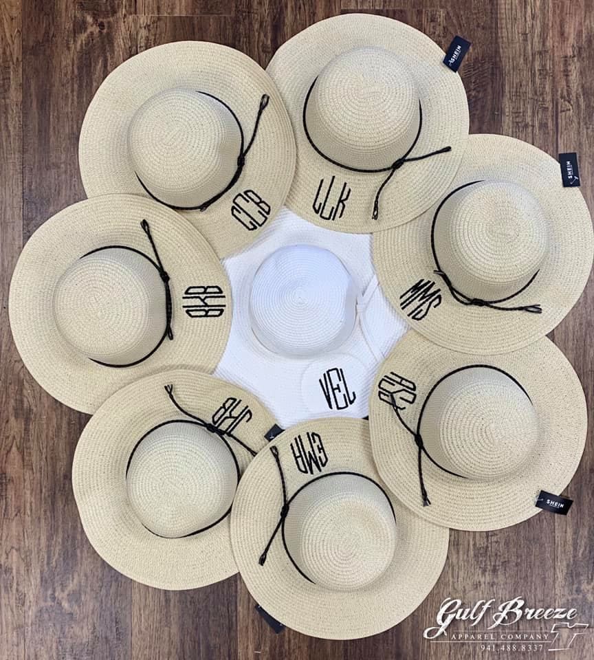 Six beige sun hats arranged in a flower pattern on a wooden background.