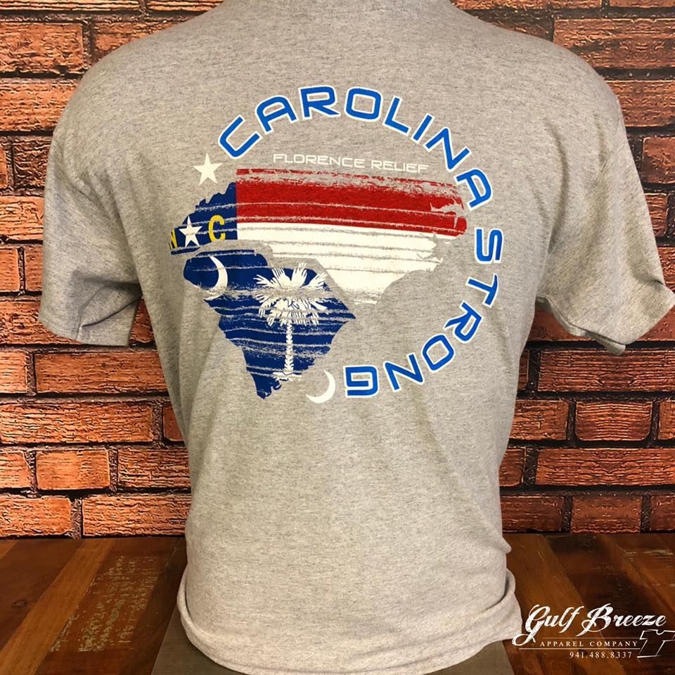 Gray T-shirt with a South Carolina flag graphic and “CAROLINA STRONG” text on the back against a brick wall