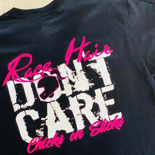 Black T-shirt with pink and white text reading “Race Hair Don’t Care Chicks on Slicks.”