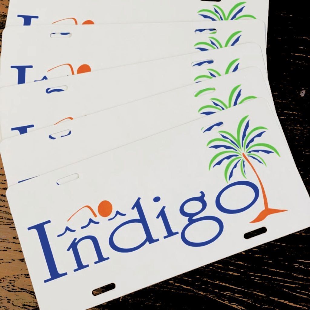 White “Indigo” sign with blue and orange lettering and palm tree graphics on a display board.