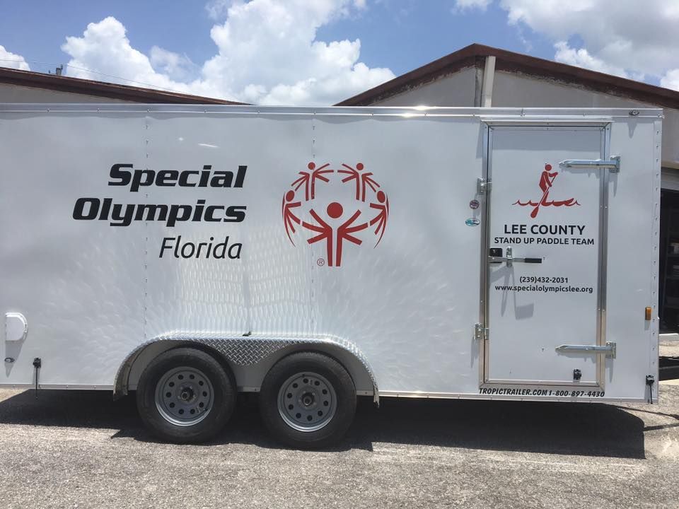 Special Olympics Florida trailer with Lee County logo, parked outdoors under a blue sky.