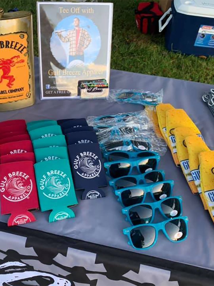 Table display with colorful branded socks, blue sunglasses, and a can of Brezzy drink at an outdoor event