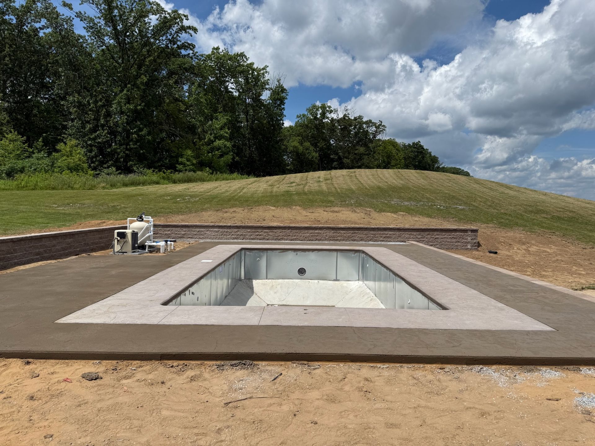An empty, rectangular swimming pool under construction in a grassy field.
