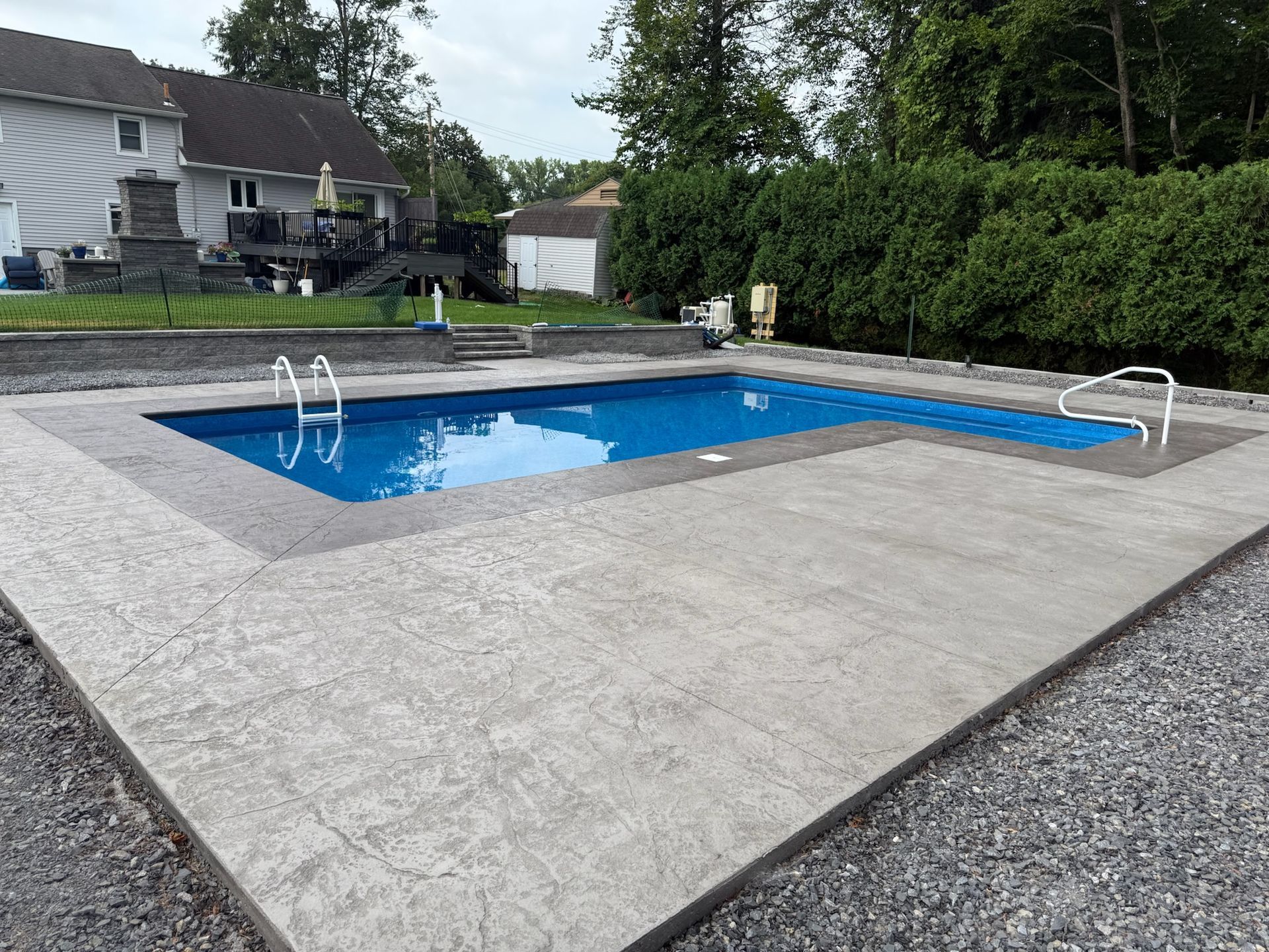A rectangular in-ground swimming pool with blue water and gray concrete deck.