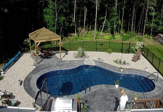 Overhead view of a kidney-shaped pool with gazebo and surrounding landscaping, trees in background.