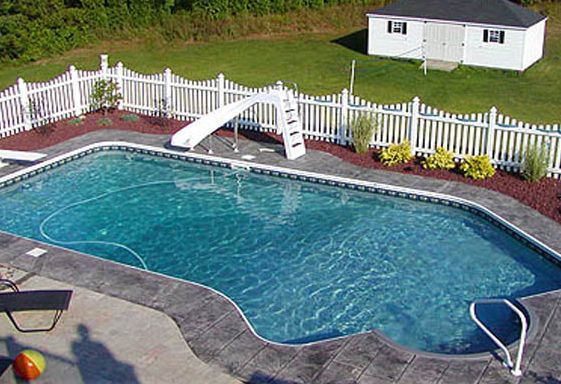 Rectangular swimming pool with slide, white picket fence, and small white shed in a backyard.