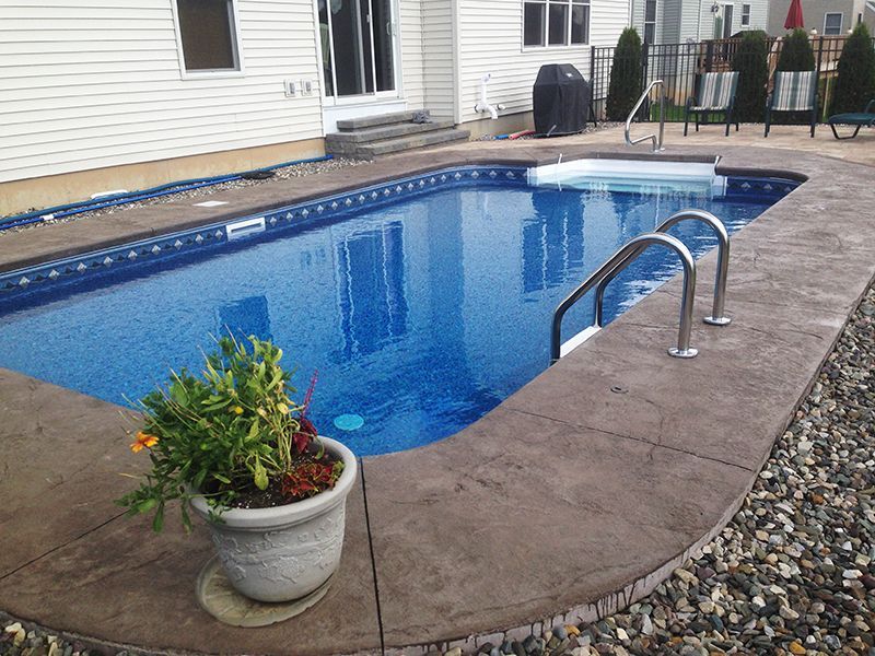 Swimming pool with blue interior, concrete border, and potted plant.