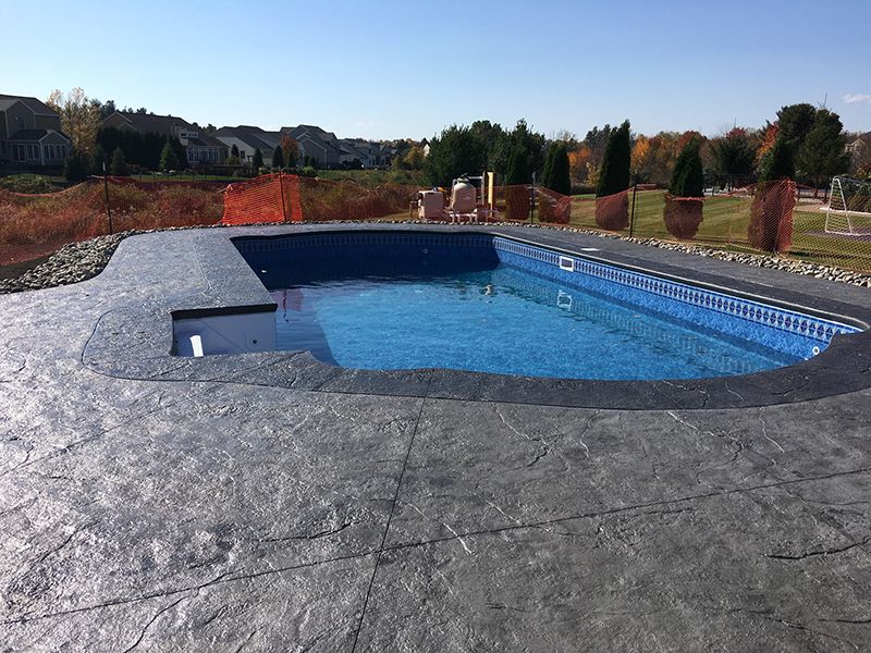 Empty rectangular pool with blue tiled interior surrounded by gray concrete patio.