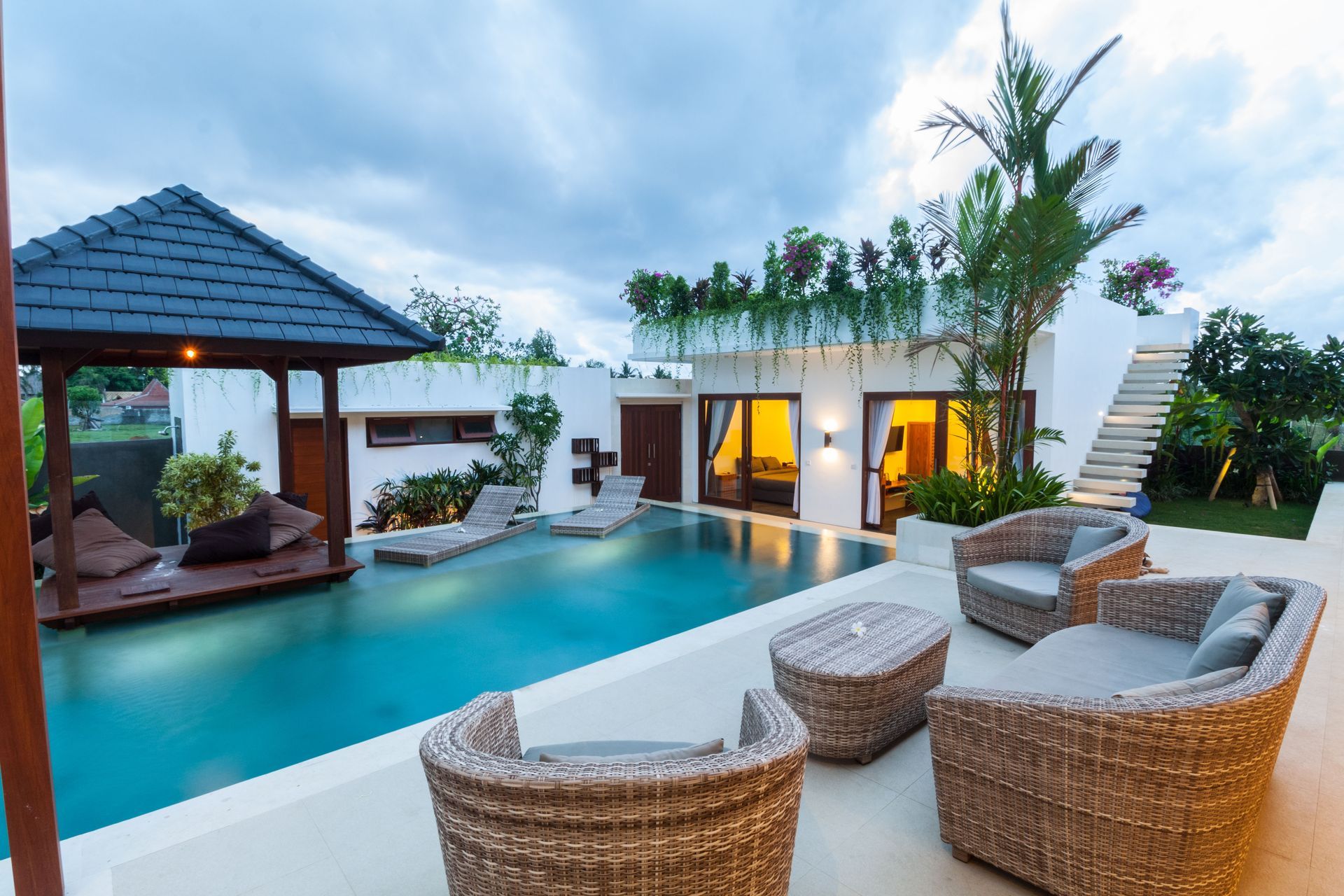 A luxurious villa with a pool and lounge area at dusk.