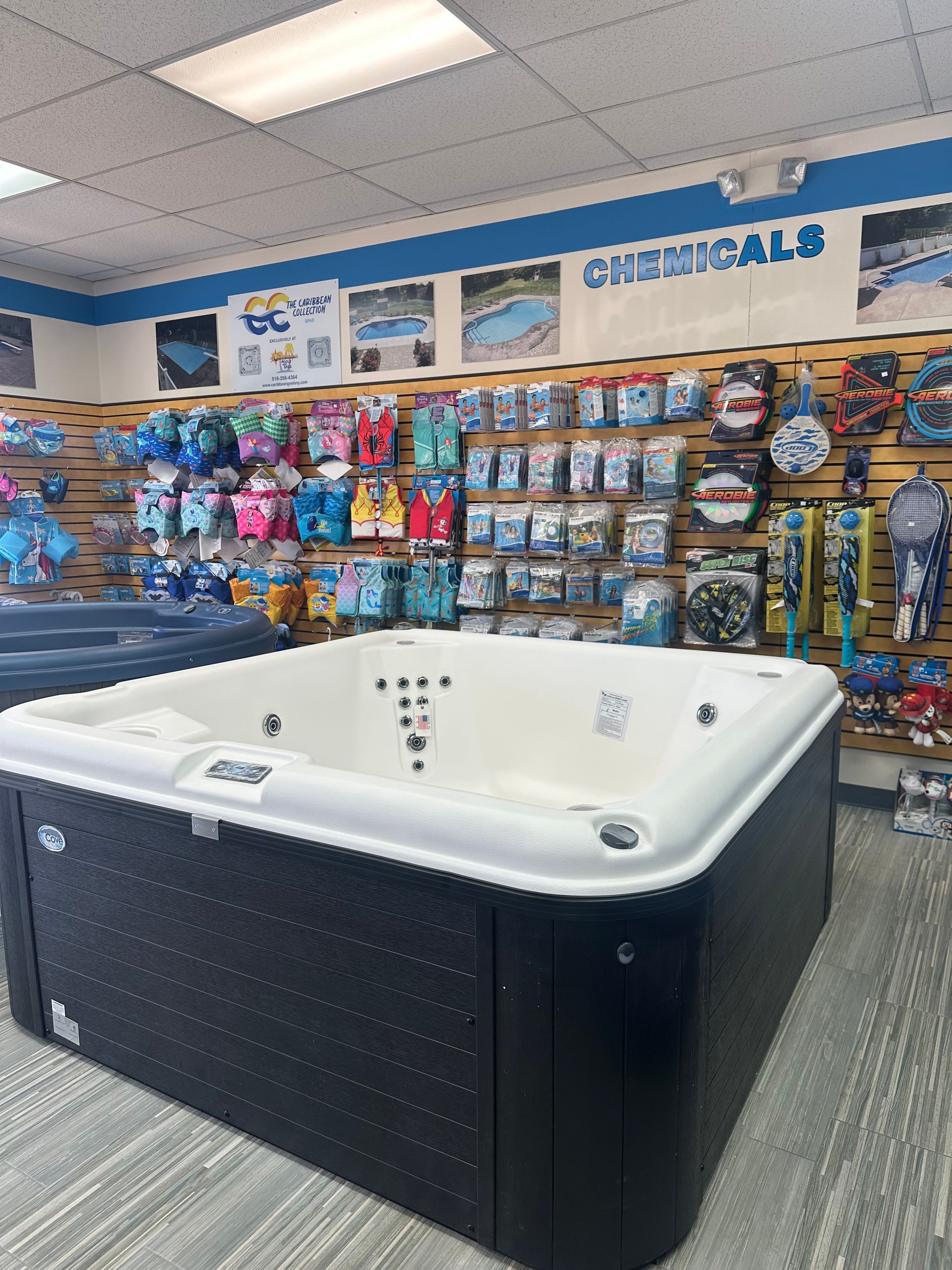 A hot tub in a store, surrounded by swimming pool supplies. Black and white tub with jets.