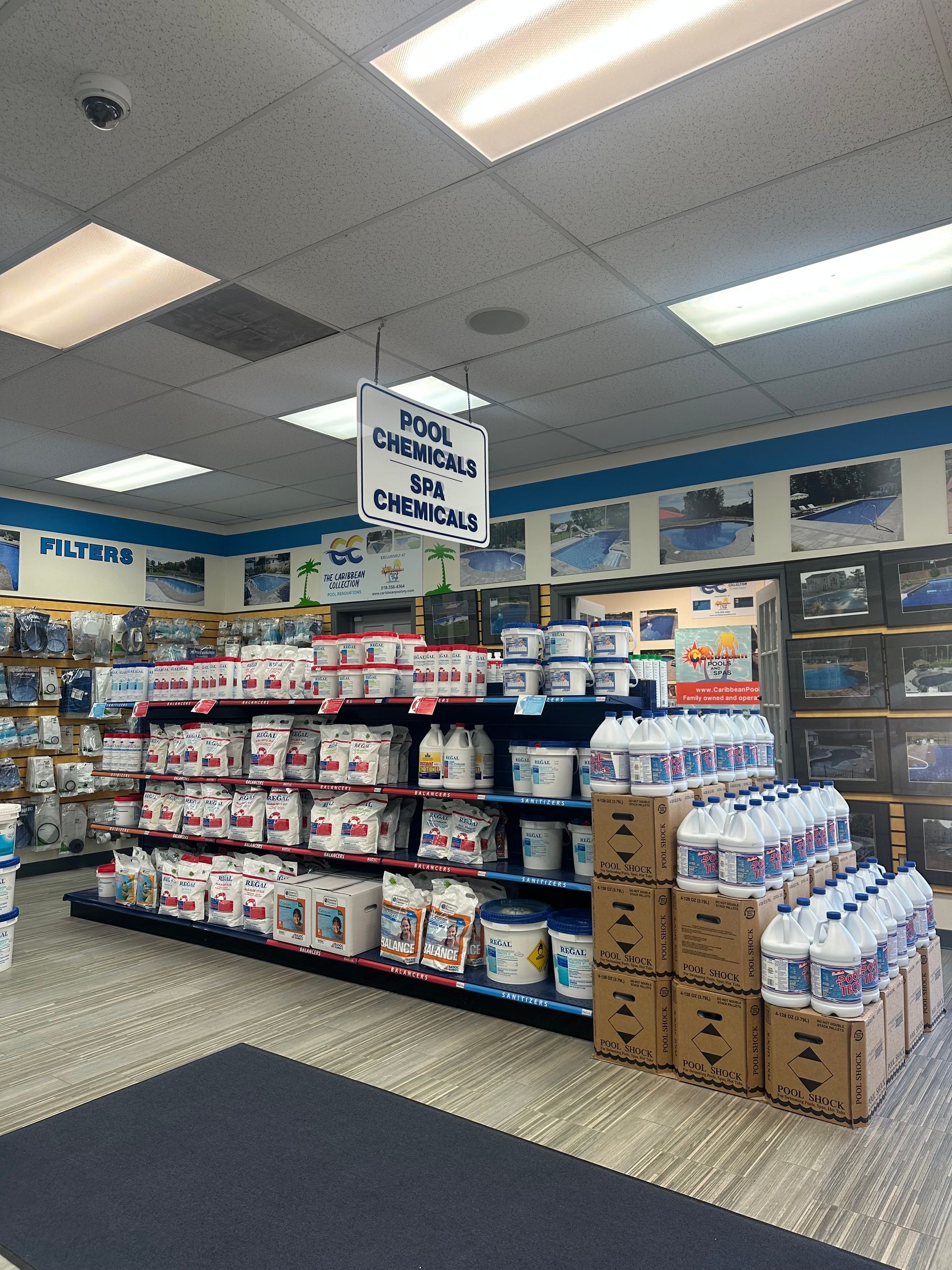 Pool chemicals aisle in a store, with shelves of products, boxes, and a hanging sign.