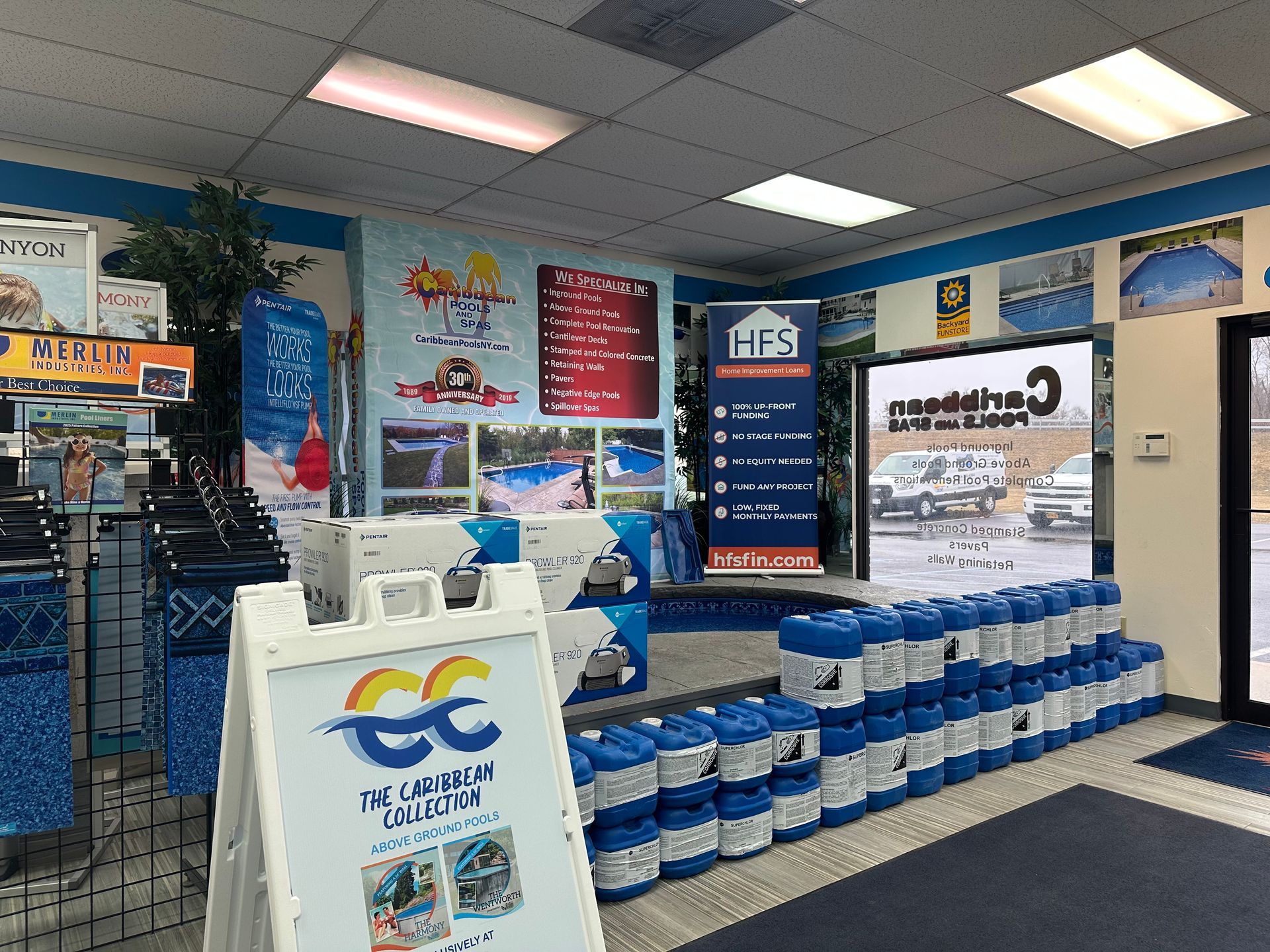 Pool supply store interior with products on display, including chemicals, signage, and an open door.