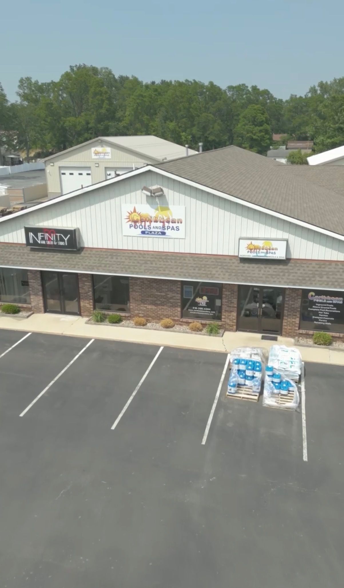 A commercial building with three business signs above storefront windows in front of a parking lot.