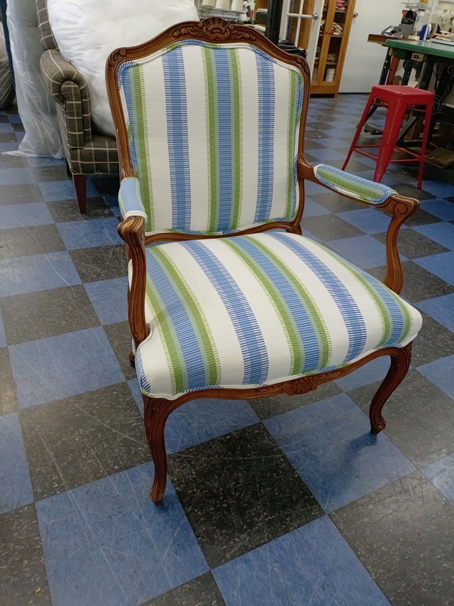 A blue and green striped chair is sitting on a checkered floor.