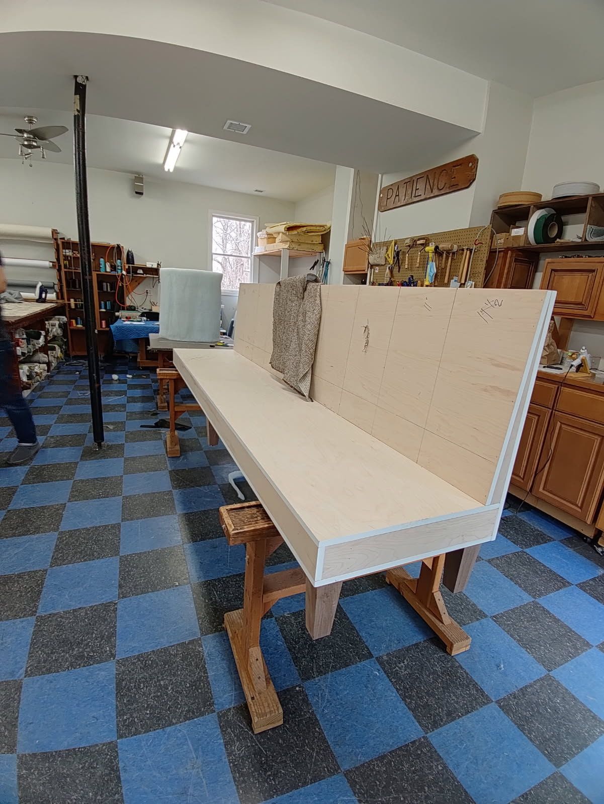 A wooden bench is sitting on a checkered floor in a room.