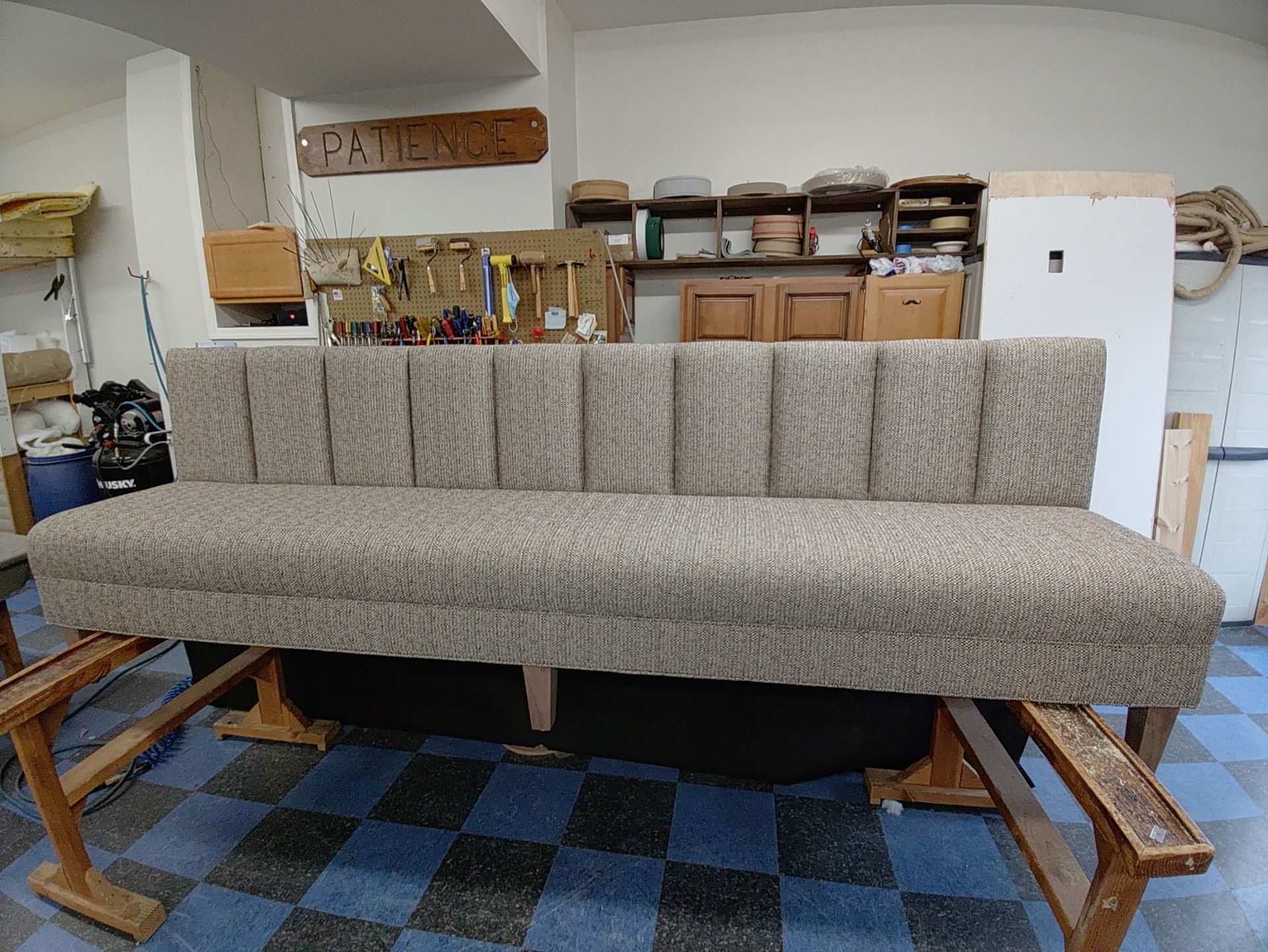 A couch is sitting on a checkered floor in a room.