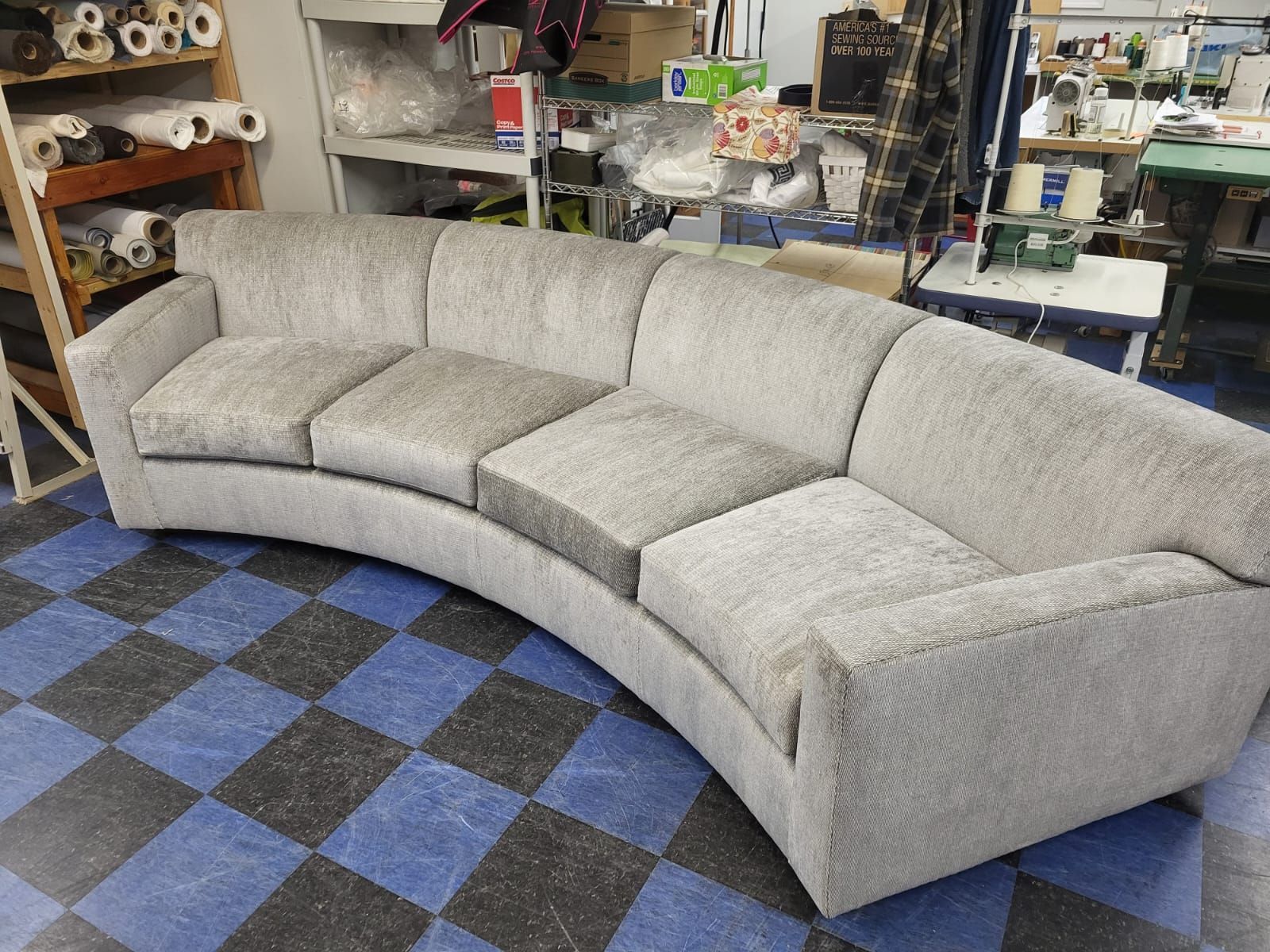 A curved couch is sitting on a checkered floor in a room